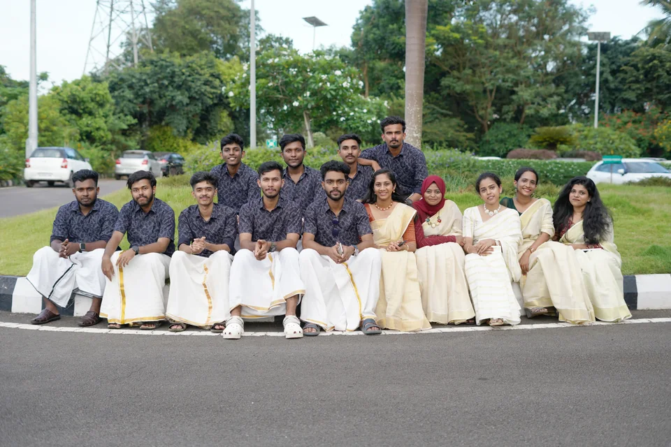 Trogon teammates in traditional Kerala attire sitting together outdoors