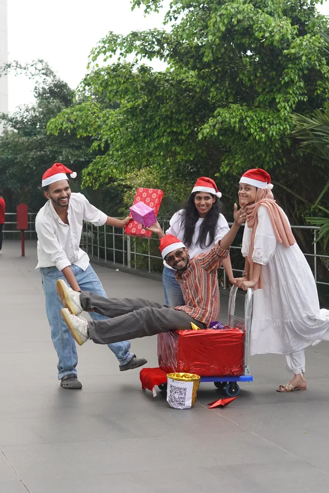 Teammates in Santa hats having fun with wrapped Christmas gifts